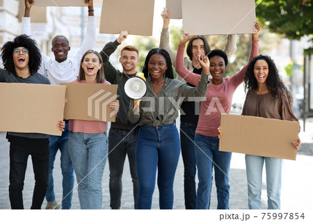 Positive international students walking by street with empty placards Positive international students walking by street with empty placards 75997854