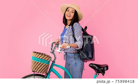 Smiling asian woman standing with retro bicycle with wicker basket 75998418