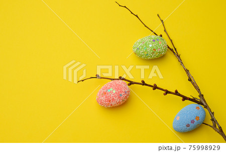 decorative easter eggs hang on a branch, yellow background decorative easter eggs hang on a branch, yellow background 75998929