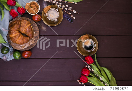Easter breakfast with aromatic fresh espresso, croissants, colored eggs, red tulips and willow 75999374