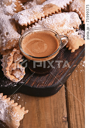 Carnival food TYPICAL and aromatic coffee. Sfrappole or chiachiere or angel wings on a woody 75999375