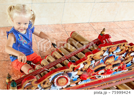Child play music on traditional indonesian bamboo xylophone Rindik. 75999424