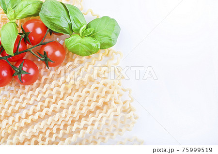 Pasta with fresh tomatoes, basil and olive oil on light shabby rustic background, top view, border Pasta with fresh tomatoes, basil and olive oil on light shabby rustic background, top view, border 75999519