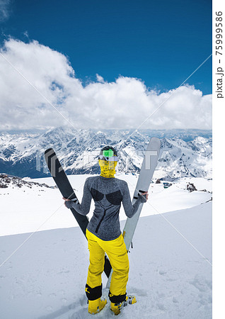 sports girl stands and holds skis against the background of mountains 75999586