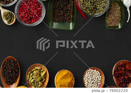 Various exotic spices in wooden spoons on dark background 76002220