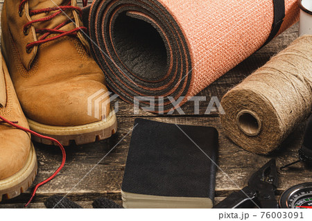 Hiking boots and rope hank on wooden board 76003091