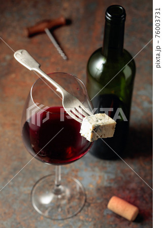 Blue cheese on a fork and red wine. 76003731