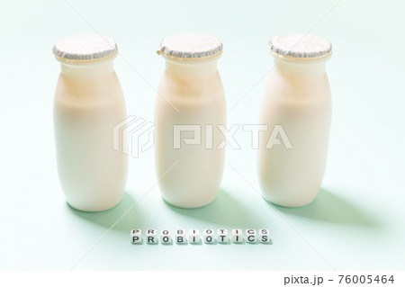 Small bottles with probiotics and prebiotics dairy drink on blue background. Production with biologically active additives. Fermentation and diet healthy food. Bio yogurt with useful microorganisms. Small bottles with probiotics and prebiotics dairy drink on blue background. Production with biologically active additives. Fermentation and diet healthy food. Bio yogurt with useful microorganisms. 76005464