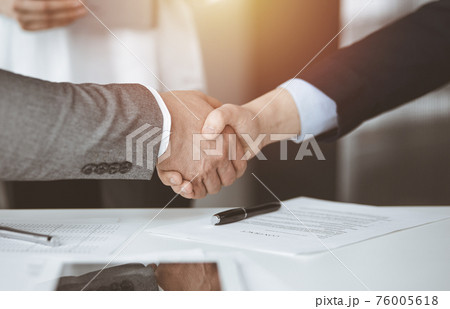 Business people shaking hands finishing contract signing in sunny office, close-up. Handshake and marketing Business people shaking hands finishing contract signing in sunny office, close-up. Handshake and marketing 76005618