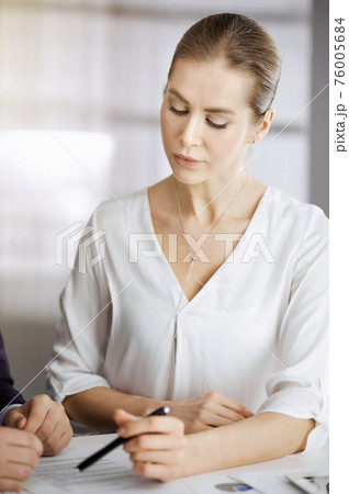 Business people discussing something while sitting in sunny office. Focus at businesswoman while talking to her male colleague 76005684