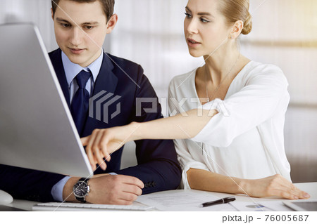 Business people discussing something while sitting in sunny office. Focus at businesswoman while talking to her male colleague 76005687