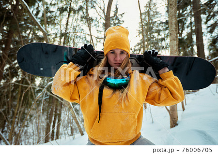 Woman snowboarder in bright suit in a sports glasses holds a snowboard. Extreme sports. Leisure. 76006705