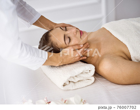 Beautiful brunette woman enjoying facial massage comfortable and bissfulle. Relaxing treatment in medicine and spa center concepts 76007702
