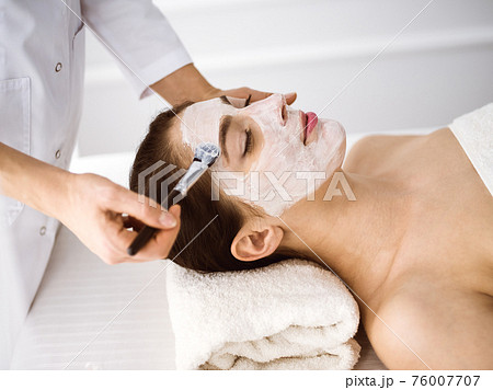 Beautiful brunette woman enjoying applying cosmetic mask comfortable and bissfulle. Relaxing treatment in medicine and spa center concepts 76007707