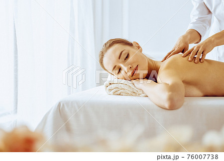 Beautiful woman enjoying back massage with closed eyes. Spa treatment concept Beautiful woman enjoying back massage with closed eyes. Spa treatment concept 76007738