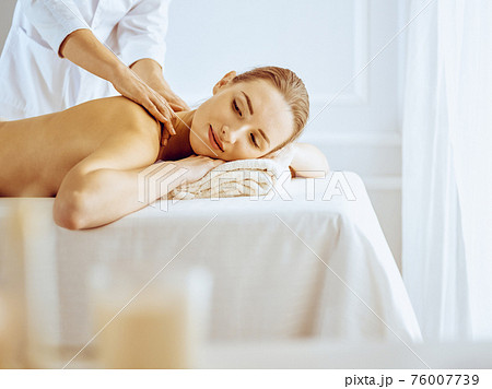 Beautiful woman enjoying back massage with closed eyes. Spa treatment concept Beautiful woman enjoying back massage with closed eyes. Spa treatment concept 76007739