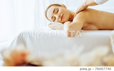 Beautiful woman enjoying back massage with closed eyes. Spa treatment concept Beautiful woman enjoying back massage with closed eyes. Spa treatment concept 76007740