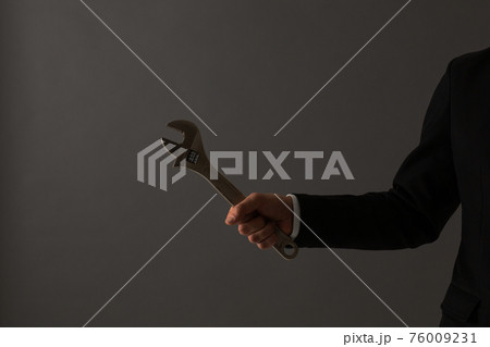 レンチを持つ男性　スーツ　手元 76009231