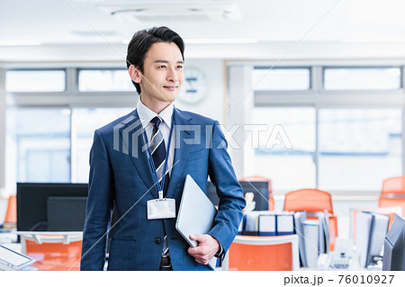 スーツを着てオフィスに立つ男性のビジネスイメージ 76010927