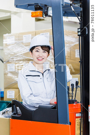 ヘルメットを被りフォークリフトを操作する女性 76011135