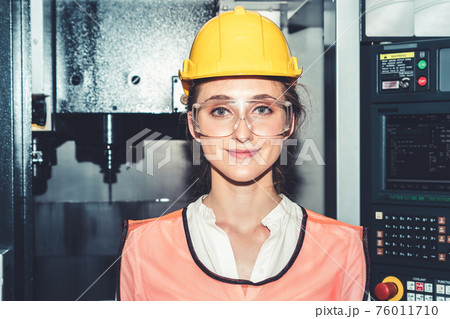 Young woman factory worker close up portrait in manufacturing job factory Young woman factory worker close up portrait in manufacturing job factory 76011710