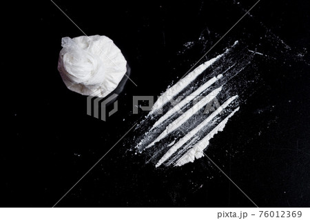 white powder (heroin, cocaine, narcotic) in a plastic bag on a black background, drugs are scattered in the form of a track white powder (heroin, cocaine, narcotic) in a plastic bag on a black background, drugs are scattered in the form of a track 76012369