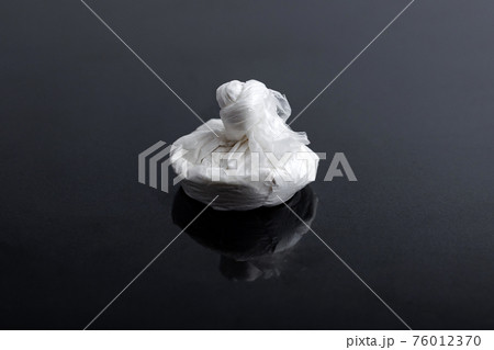 white powder (heroin, cocaine, narcotic) in a plastic bag on a black background 76012370