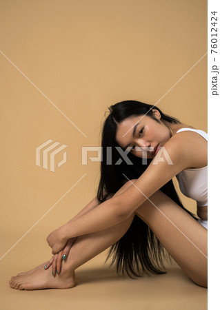 Brunette woman wearing white lingerie sitting at the floor while posing 76012424