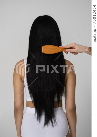 Woman standing at the studio while somebody unrecognizable brushing her hair Woman standing at the studio while somebody unrecognizable brushing her hair 76012454