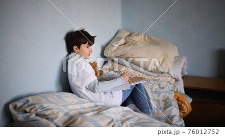 Poor sad small girl on bed indoors at home, poverty concept. Poor sad small girl on bed indoors at home, poverty concept. 76012752