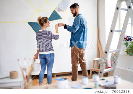 Couple having fun when painting wall indoors at home, relocation and diy concept. Couple having fun when painting wall indoors at home, relocation and diy concept. 76012853