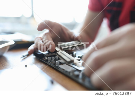 Master conducting diagnostics of video card in workshop closeup 76012897