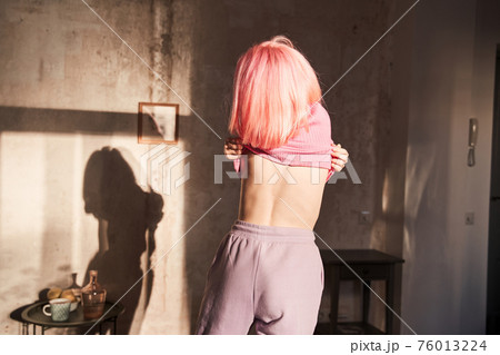 Woman with pink hair change her clothes at the sunny room at the morning 76013224