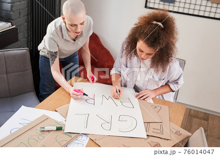 Girls drawing handmade poster about feminism at the table with each other Girls drawing handmade poster about feminism at the table with each other 76014047