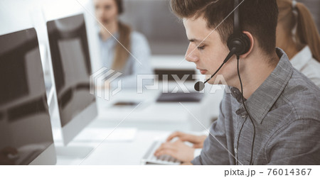 Call center. Group of casual dressed operators at work. Businessman in headset at customer service office. Telesales in business Call center. Group of casual dressed operators at work. Businessman in headset at customer service office. Telesales in business 76014367