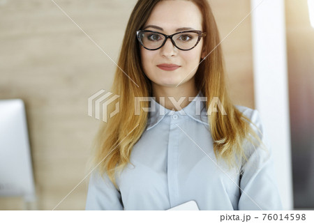 Business woman headshot in sunny office. Unknown businesswoman standing straight with tablet computer. Young accountant or secretary looks good 76014598