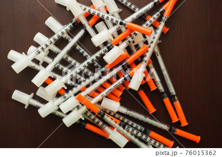 Pile of Medical syringes on wooden background. 76015362