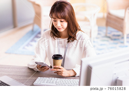 デスクワーク中にスマホを操作する女性 76015828