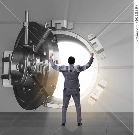 Businessman in front of banking vault door 76018297