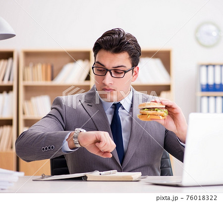 Hungry funny businessman eating junk food sandwich Hungry funny businessman eating junk food sandwich 76018322