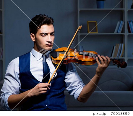 Young musician man practicing playing violin at home Young musician man practicing playing violin at home 76018399
