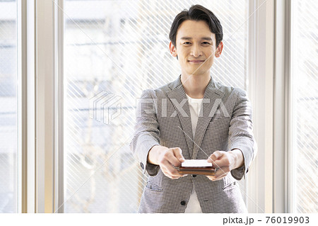 名刺を差し出す男性（正面） 76019903