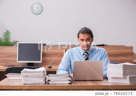 Young male employee unhappy with excessive work 76020273