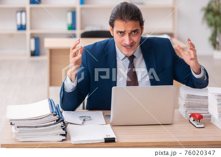 Young male employee unhappy with excessive work 76020347