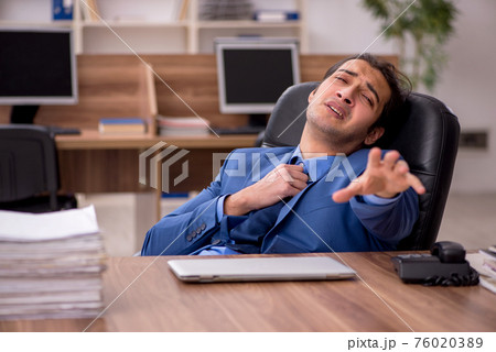 Young male employee and a lot of work in the office 76020389