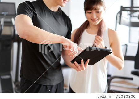 タブレットを使って指導するアジア人男性パーソナルトレーナー 76020800