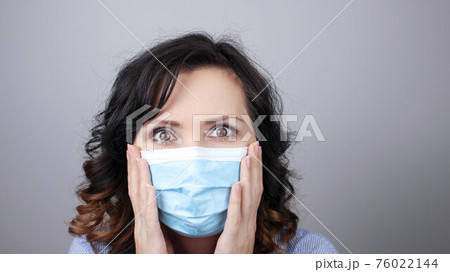 Woman wearing protection face mask against coronavirus. Woman in a mask looking shocked or worried with hands up. Medical mask, Close up shot, Select focus, Prevention from covid19 76022144