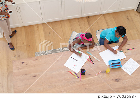 High angle view of african american brother and sister sitting at table doing school work High angle view of african american brother and sister sitting at table doing school work 76025837
