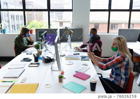 Diverse group of business people wearing face masks in creative office 76026259