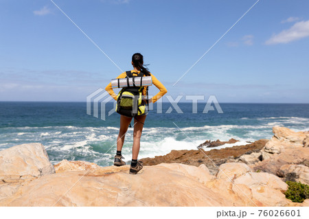 Fit afrcan american woman wearing backpack hiking on the coast Fit afrcan american woman wearing backpack hiking on the coast 76026601